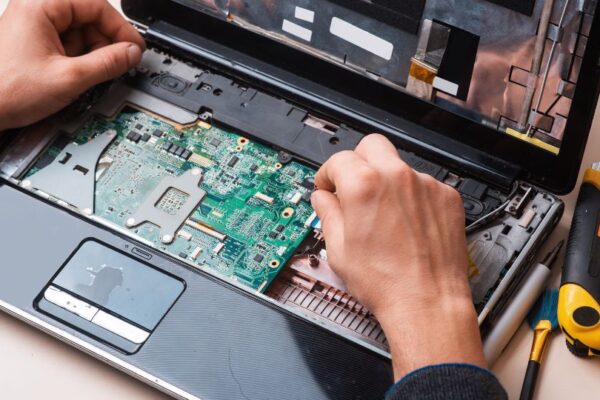 Kéz egy laptop belsejében, processzor cseréjéhez szükséges alkatrészekkel.