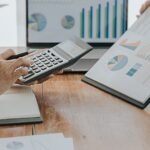 Két ember üzleti tervet készít, számológépet és grafikonokat használnak.